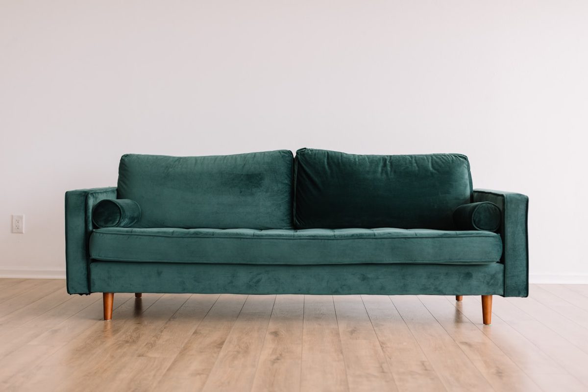 Three-seat emerald green velvet sofa with tapered wood legs